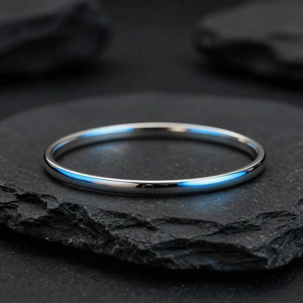 Bracciale in acciaio argentato su pietra nera, luce drammatica e riflesso morbido